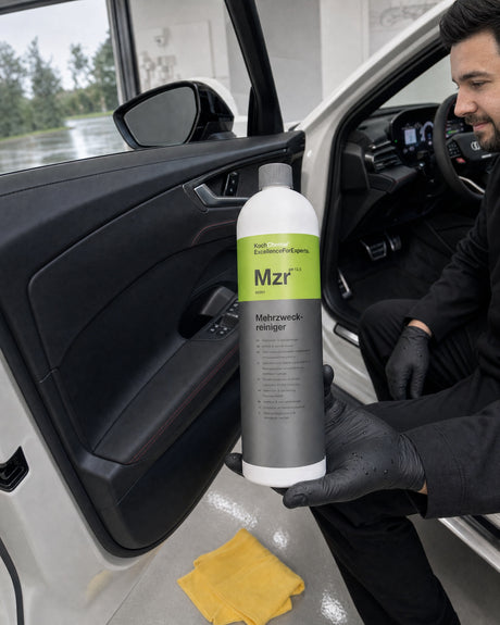 Koch-Chemie allesreiniger Mzr in Daniels hand bij de open instap van de witte Audi RS 5, deurpaneel diepzwart.