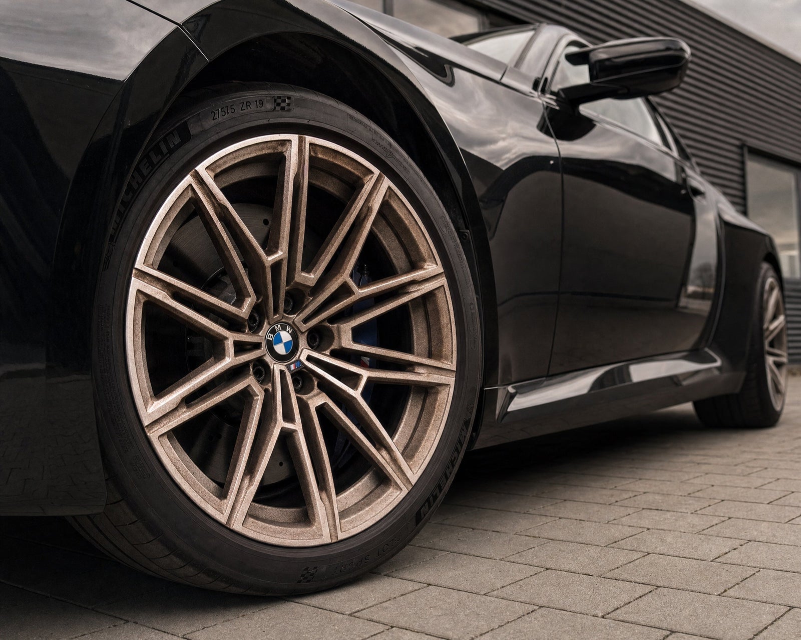 Rostbrauner Bremsstaub-Film auf der silbernen Alufelge eines schwarzen BMW M2 — gezeigt im Artikel „Alufelgen reinigen: welche Oberfläche du wirklich hast“