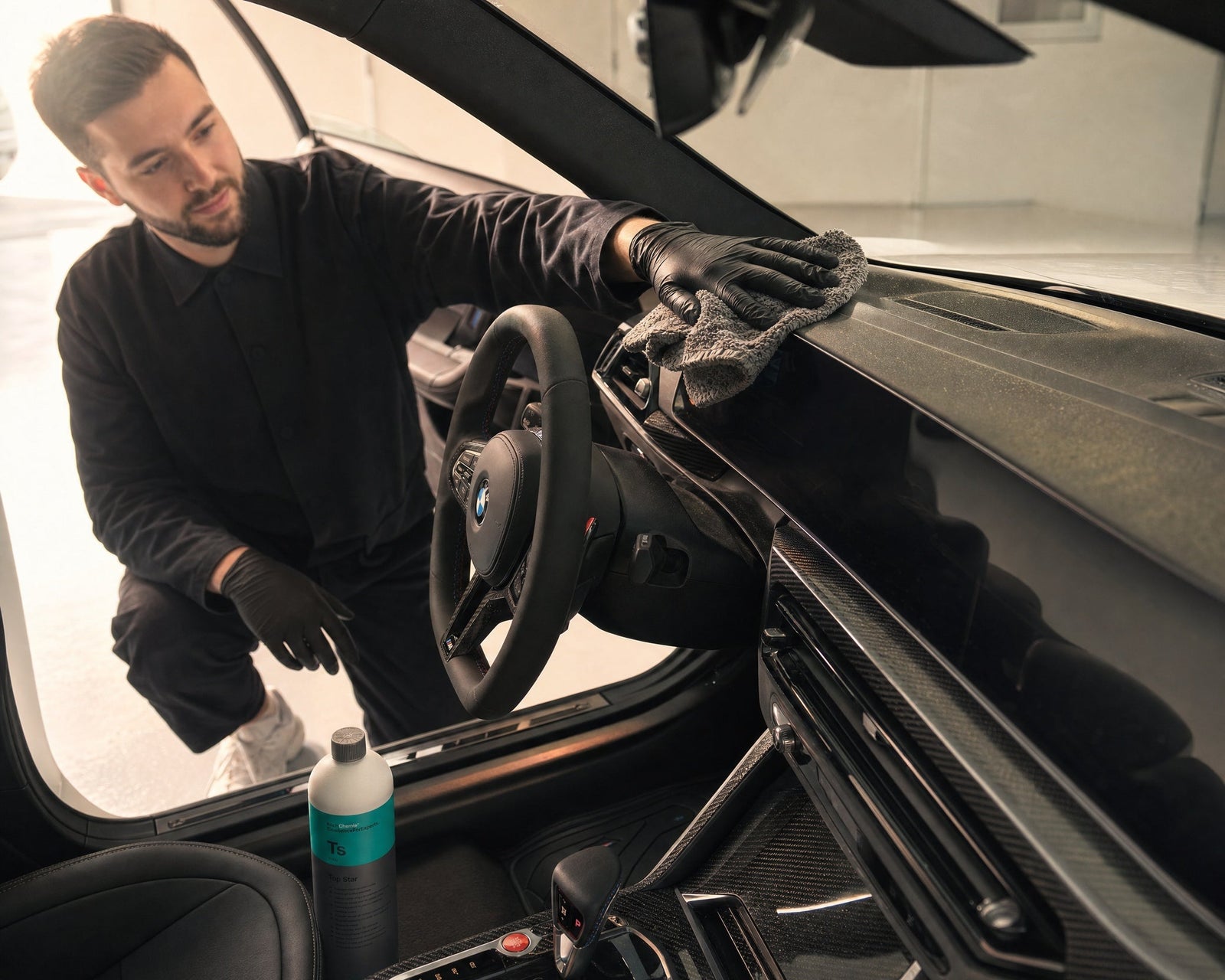 Daniel wischt in der Pollensaison den gelben Pollenfilm vom Armaturenbrett eines weißen BMW M2 — gezeigt im Artikel „Auto-Innenraum in der Pollensaison reinigen: Cockpit, Lüftung, Filter“