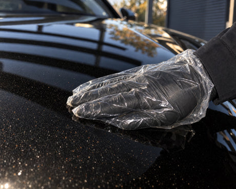 Detailing1 voeltest op zwarte Audi RS 5 — hand in plastic zakje over vliegroest en industriestof op de motorkap
