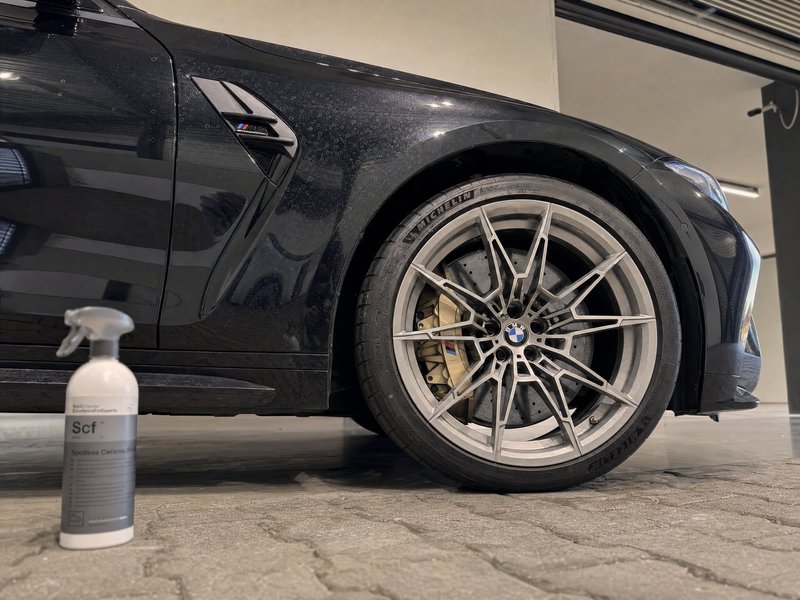 Zwarte BMW M3 met watervlekken op de keramische coating naast Koch-Chemie Spotless Ceramic Finish