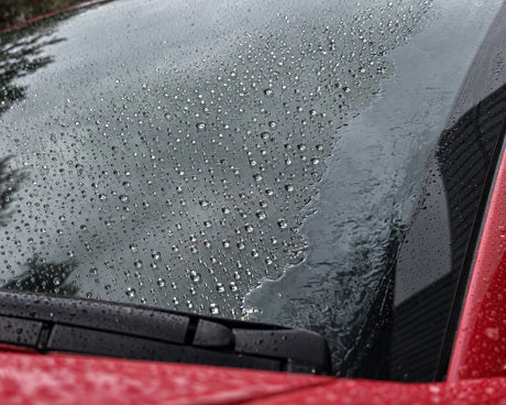 Regenabweiser im Test: Tropfen perlen auf versiegeltem Glas, am unversiegelten Rand liegt ein Wasserfilm