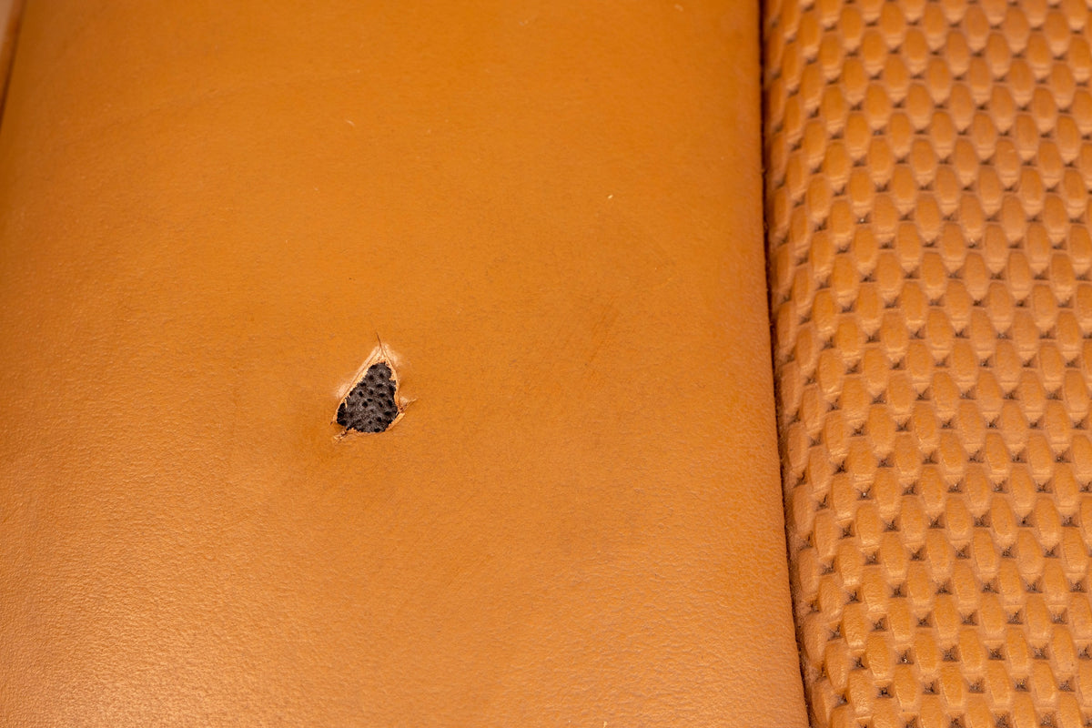 Detailing1 COLOURLOCK Fluid Leather — Brandloch in einem cognacfarbenen, perforierten Ledersitz