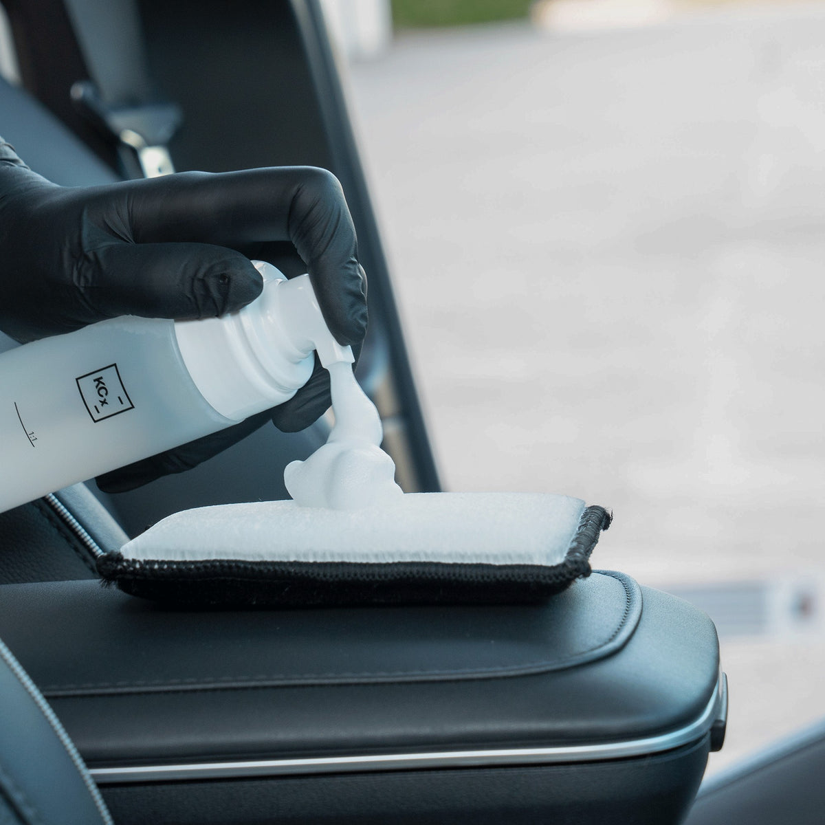 Detailing1 COLOURLOCK Leather Cleaner (Mild) — cleaning foam on the pad next to a black leather armrest
