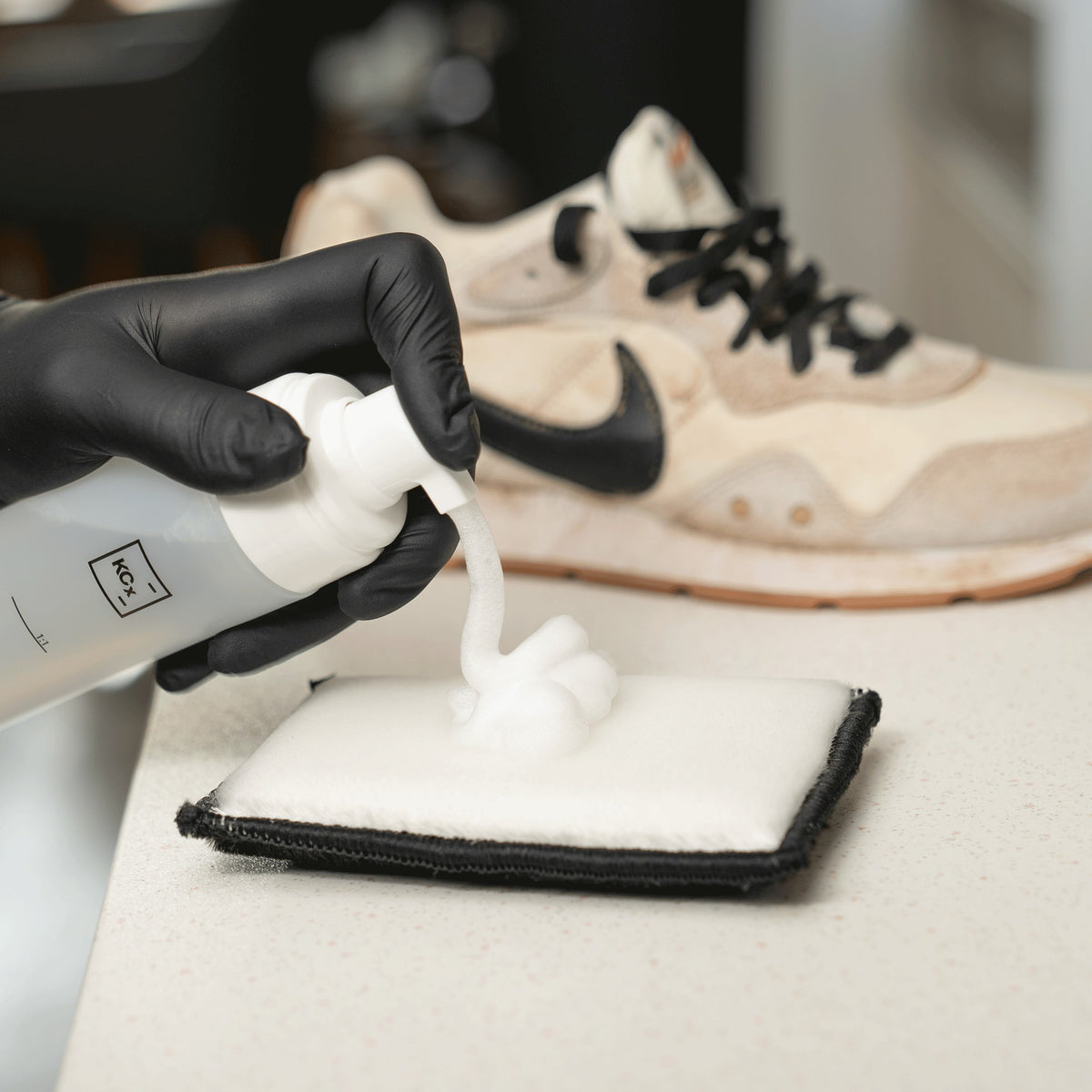 Detailing1 COLOURLOCK Sneaker reinigen — Reinigungsschaum auf dem Pad, dahinter der verschmutzte Sneaker